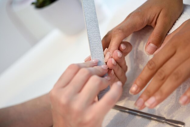 Foto gekapte handen die de nagels van klanten vormen