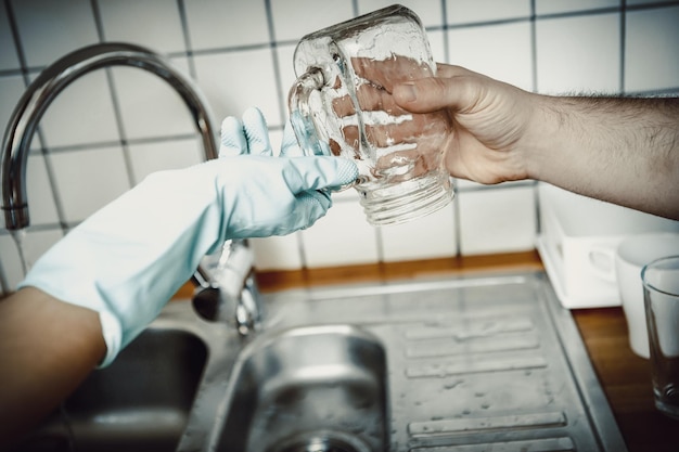 Foto gekapte handen die een potje vasthouden in de keuken.