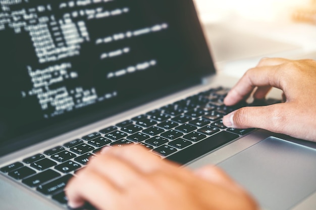 Foto gekapte handen van een computerprogrammeur met een laptop op tafel