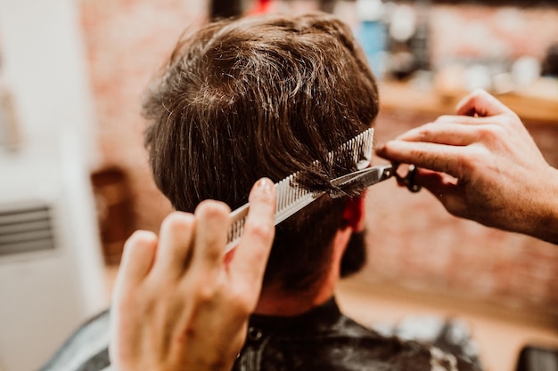 Gekapte handen van een kapper die een klant in een salon verzorgt