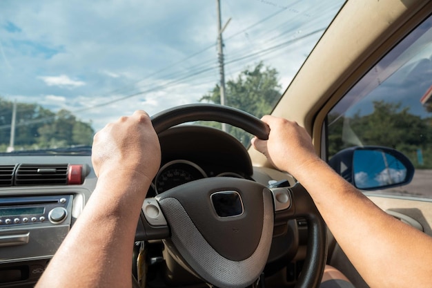 Gekapte handen van een man die een auto rijdt.