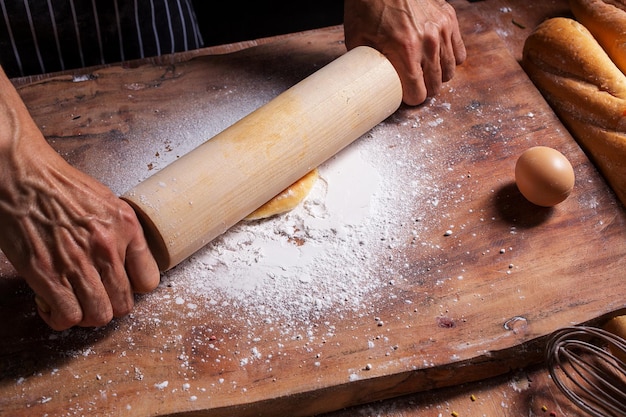 Foto gekapte handen van een man die eten aan tafel bereidt