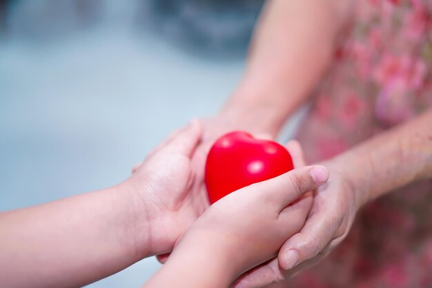 Foto gekapte handen van een meisje die een rood hart vorm geeft aan oma.