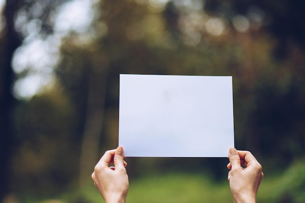 Foto gekapte handen van een persoon die een blank papier vasthoudt