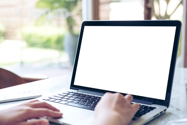 Foto gekapte handen van een persoon die een laptop op tafel gebruikt