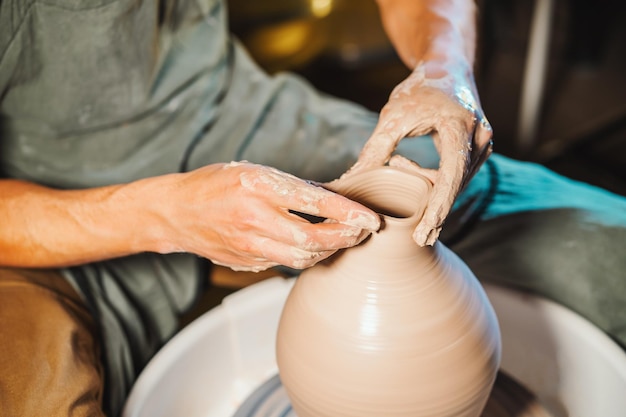 Gekapte handen van een pottenbakker die potten maakt in een pottenbakkerswerkplaats