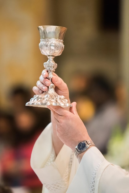 Gekapte handen van een priester die de kelk vasthoudt in de kerk