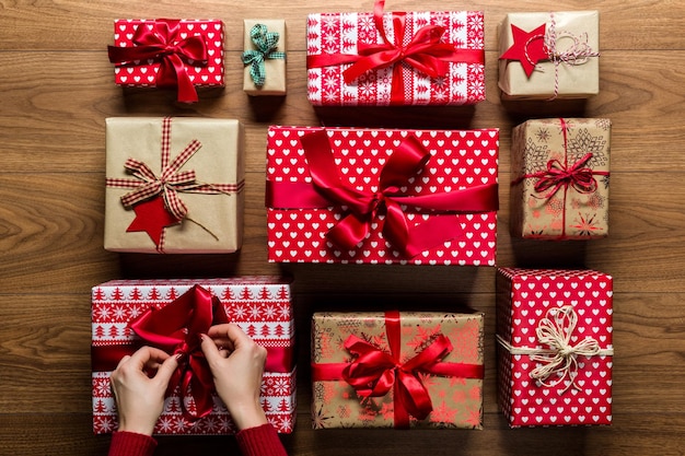 Gekapte handen van een vrouw die kerstcadeaus op een hardhouten vloer rangschikt