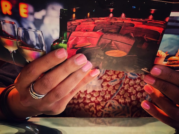 Foto gekapte handen van een vrouw met een foto in een restaurant