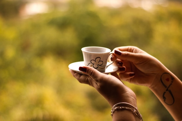 Foto gekapte handen van een vrouw met een koffiekop buiten