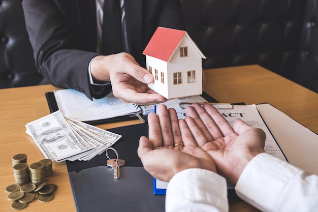 Gekapte handen van een zakenman die een model naar huis neemt van een mannelijke collega op kantoor.