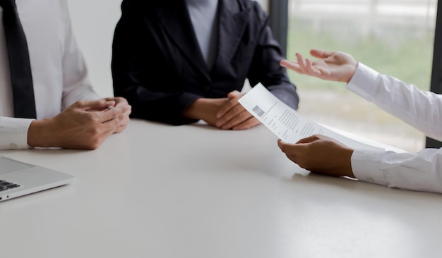 Gekapte handen van een zakenman die kandidaten interviewt aan een bureau in zijn kantoor.