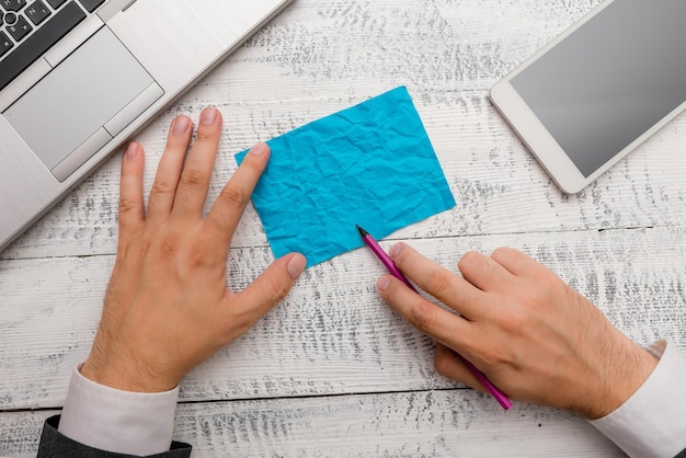 Foto gekapte handen van een zakenman met leeg blauw papier op het bureau.