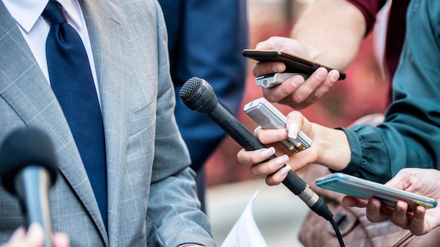 Foto gekapte handen van journalisten die een zakenman interviewen in de stad.