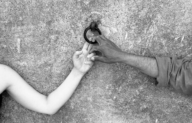 Foto gekapte handen van mensen die een metalen ring in de muur houden