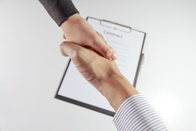 Foto gekapte handen van mensen die elkaar de hand schudden aan het bureau in het kantoor.