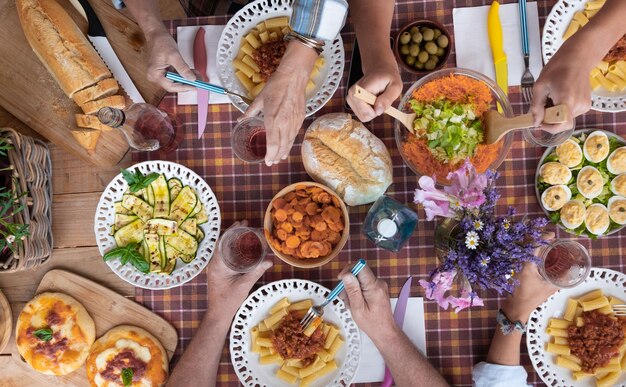 Foto gekapte handen van mensen die eten op tafel hebben.