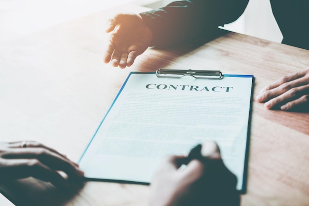 Gekapte handen van zakenlieden met een contract aan het bureau.