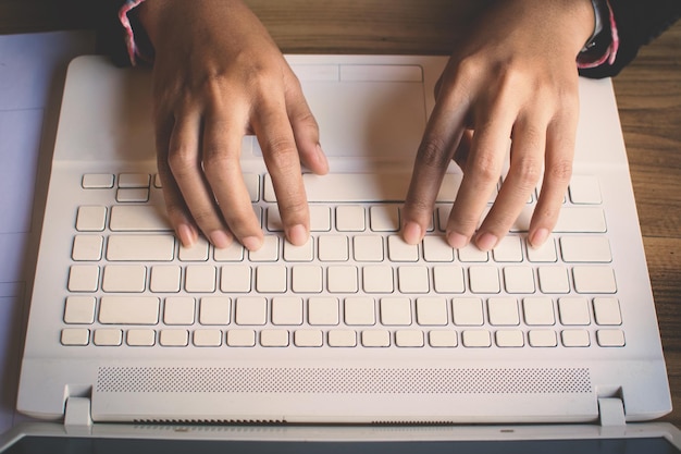 Gekapte handen van zakenvrouw met laptop op tafel op kantoor