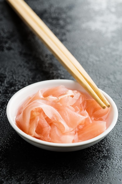Gekapte sushi gember plakjes in een schaal Roze gember op een zwarte tafel