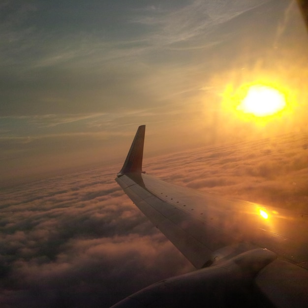 Foto gekapte vliegtuig vliegt over wolken tijdens zonsondergang