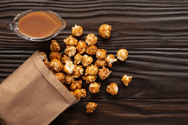 Gekarameliseerde popcorn in papieren zak op houten keukentafel plat gelegd