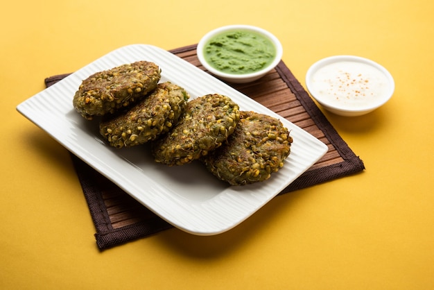 Foto gekiemde moong dal tikki of pasteitjes is een gezonde snack uit india geserveerd met groene chutney en wrongel