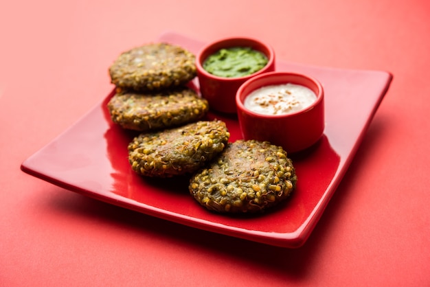 Gekiemde moong dal tikki of pasteitjes is een gezonde snack uit India geserveerd met groene chutney en wrongel