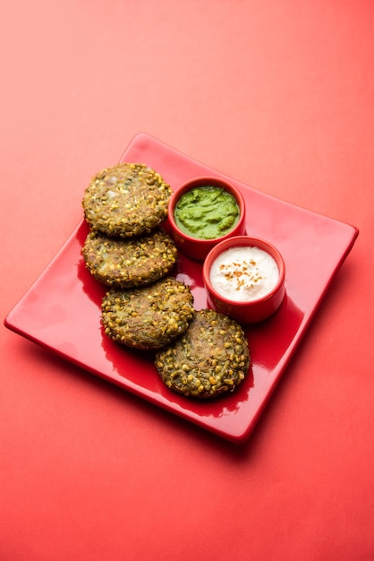 Gekiemde moong dal tikki of pasteitjes is een gezonde snack uit India geserveerd met groene chutney en wrongel