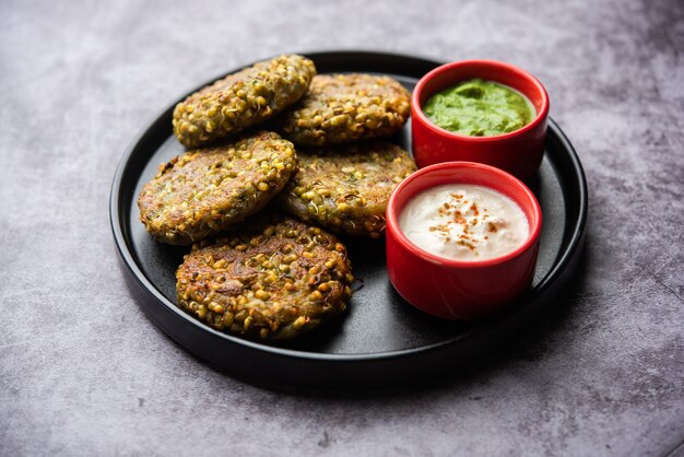 Gekiemde moong dal tikki of pasteitjes is een gezonde snack uit India geserveerd met groene chutney en wrongel