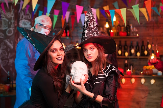 Foto gekke dokter en twee mooie heksen die halloween vieren. heksen met mooie jurken.
