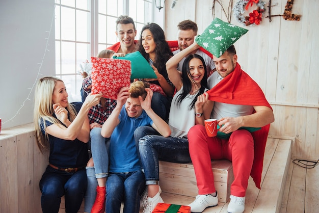 Gekke jonge beste vrienden die kussens thuis bestrijden. gemengd ras groep mensen. entertainment en levensstijl