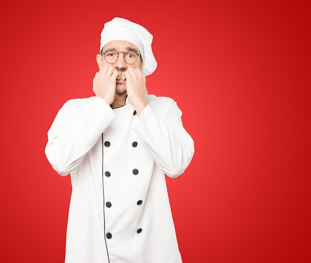 Gekke jonge chef-kok die een zenuwachtig gebaar maakt