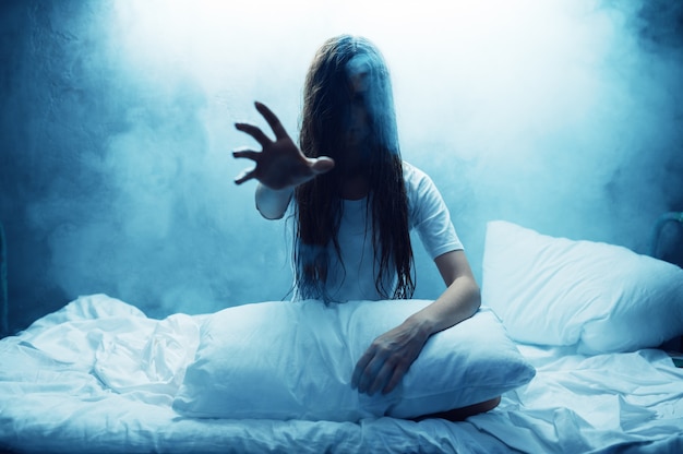 Gekke vrouw toont hand in bed, slapeloosheid, donkere rokerige kamer. psychedelische persoon die elke nacht problemen heeft, depressie en stress, verdriet, psychiatrisch ziekenhuis