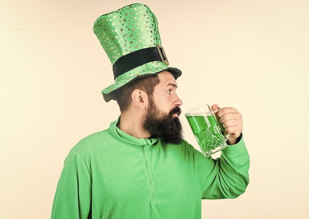 Gekleurd groen bier Groen bier onderdeel van de viering Ierse pub Alcoholconsumptie integraal onderdeel Saint Patricks Day Proost concept Ierse cultuur Man bebaarde hipster grappige hoed drink pint bier