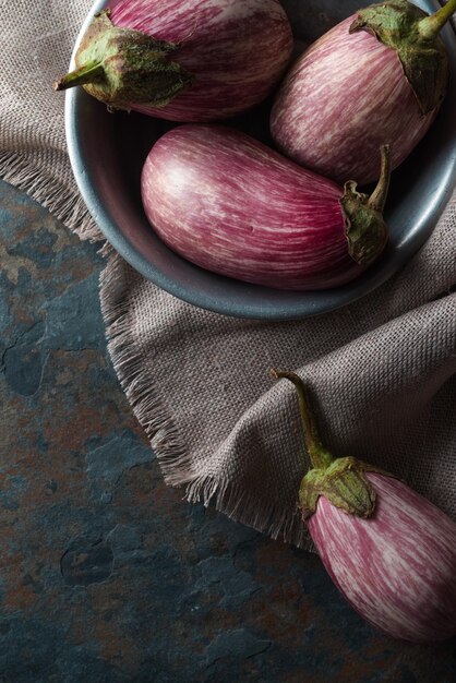 Gekleurde aubergine in een tinnen kom op een linnen servet op een blauwe steen