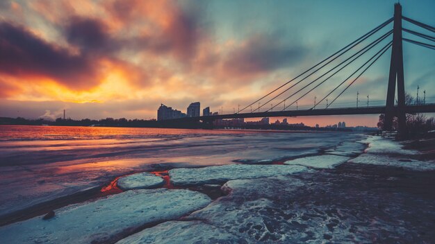 Gekleurde avondwolken drijven over half bevroren Dnipro-rivier