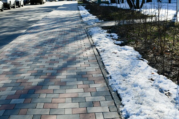 Gekleurde bestrating Lente in de stad smeltende sneeuw op het gazon