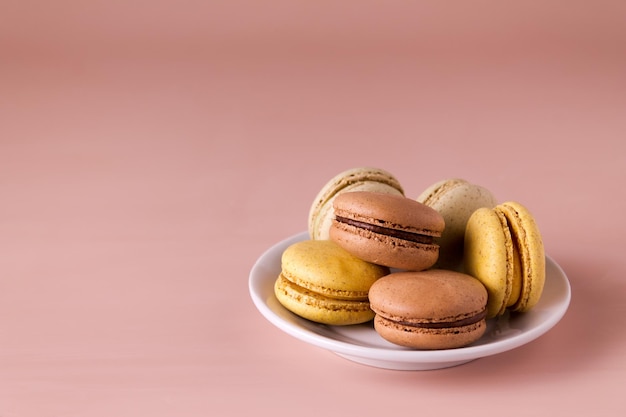 Gekleurde bitterkoekjes in een bord op een beige achtergrond kopie ruimte