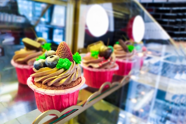 Gekleurde cupcakes met bosbessen en aardbeien op de showcase met desserts in het café. Bakken in de patisserie.