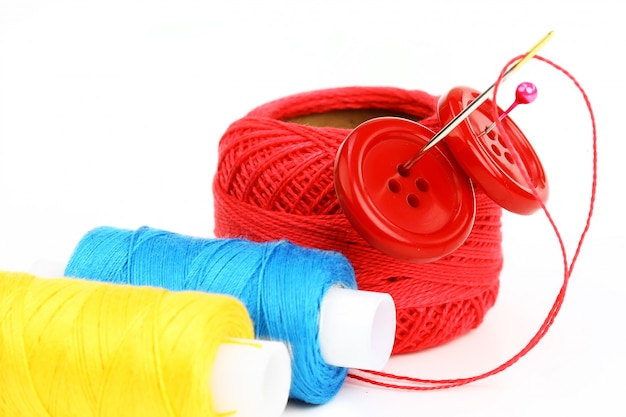 Gekleurde draden met naalden voor borduurwerk, op een witte achtergrond