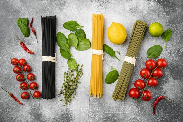 Gekleurde droge Italiaanse pasta set, op grijze stenen tafel achtergrond, bovenaanzicht plat lag