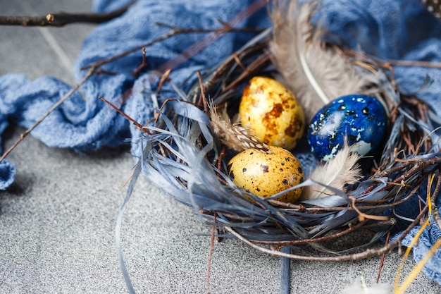 Gekleurde gele en blauwe paaseieren in kleine nesten. Kwarteleitjes voor katholieke en orthodoxe paasvakantie. Ondiepe scherptediepte.