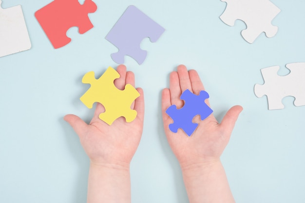 Gekleurde handen van kinderen houden puzzels op blauwe ondergrond