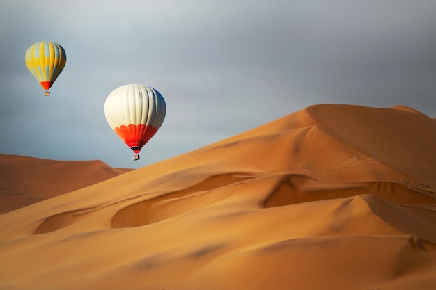 Gekleurde heteluchtballonnen die bij zonsondergang over de zandduinen vliegen