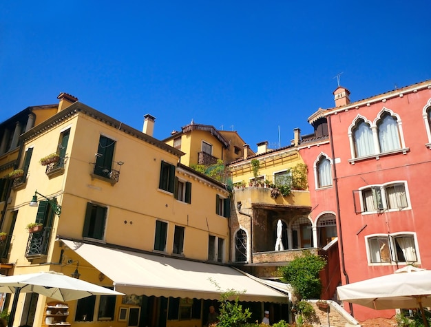 Gekleurde huizen met luifels tegen de blauwe lucht in Venetië. Italië