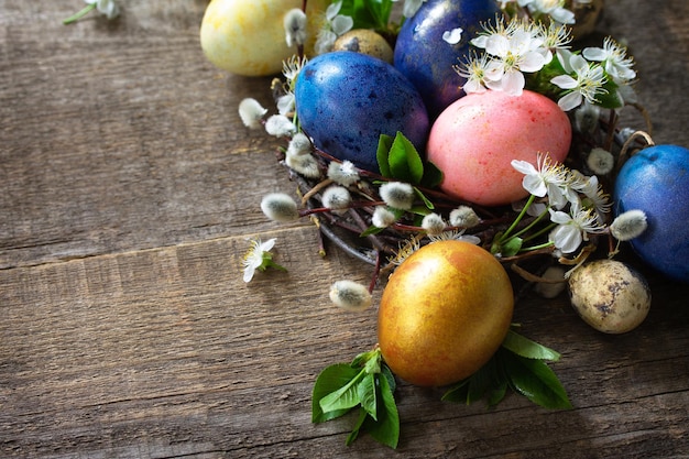 Gekleurde paaseieren in een nest met wilgentakken en lentebloemen Ruimte kopiëren