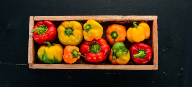 Gekleurde Paprika in een houten kist Bovenaanzicht Op een zwarte achtergrond Vrije ruimte voor tekst