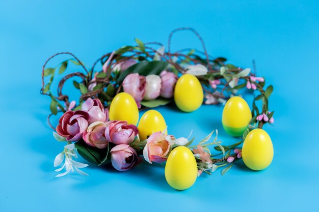Gekleurde Pasen-krans en plastic eieren op een blauwe achtergrond.