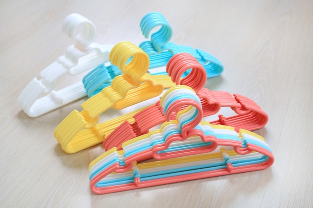 Gekleurde plastic kleerhangers op houten ondergrond